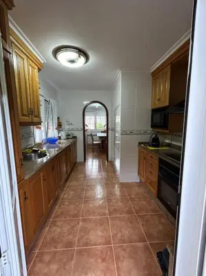 a large kitchen with wooden cabinets and a tile floor at Preciosa casa en A Caridad in La Caridad