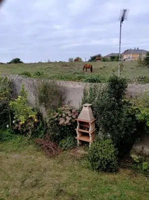 a horse grazing in a field with a bird house at Preciosa casa en A Caridad in La Caridad