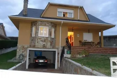 a house with a car parked in the garage at Preciosa casa en A Caridad in La Caridad