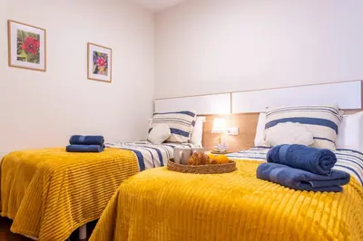 two beds in a room with yellow sheets and towels at Apartamento de playa in San Ciprián