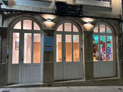 two white doors on a building with windows at Amando Perez Suites in Ribadeo