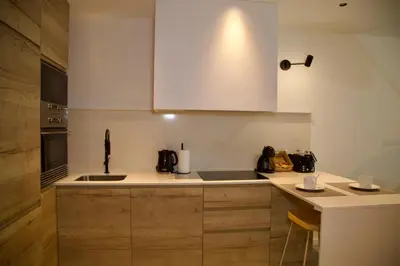 a kitchen with white cabinets and a sink at Amando Perez Suites in Ribadeo