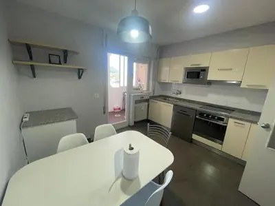 a kitchen with a white table and a white table and chairs at Piso turistico Plaza del Cine in Ponferrada