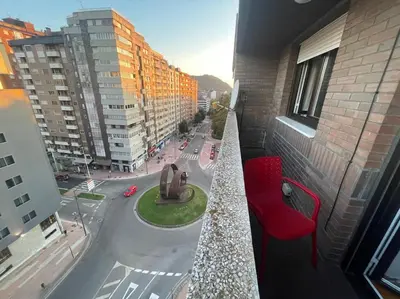 a balcony with a red chair and a view of a city at Piso turistico Plaza del Cine in Ponferrada