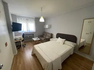 a bedroom with a bed and a living room at Piso turistico Plaza del Cine in Ponferrada