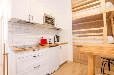 a kitchen with white cabinets and a wooden table at Soños de Compostela in Santiago de Compostela