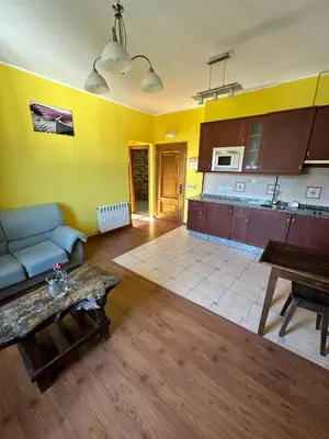 a living room with a couch and a kitchen at Apartamentos Helenias in Boal