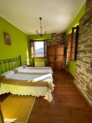 a green bedroom with two beds and a stone wall at Apartamentos Helenias in Boal