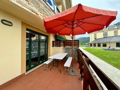 a red umbrella on a balcony with a table and chairs at Apartamento Herosa 1 Spa in Barreiros