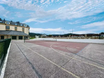 a tennis court in front of a building at Apartamento Herosa 1 Spa in Barreiros