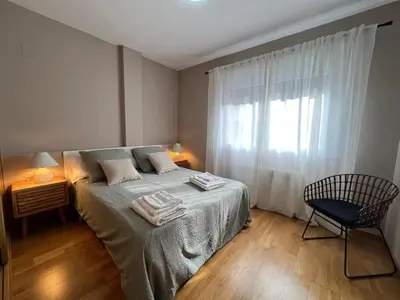 a bedroom with a bed and a chair and a window at YourHouse Lagoa in Ourense