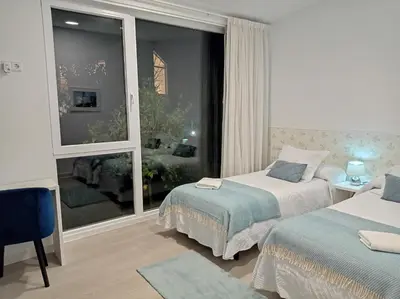 a bedroom with two beds and a large window at LAR JARDÍN - Casas independientes con parking privado in Santiago de Compostela