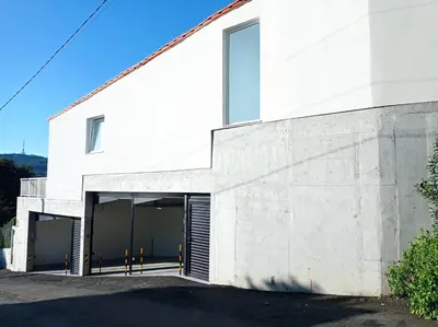 a white building with two garage doors at LAR JARDÍN - Casas independientes con parking privado in Santiago de Compostela
