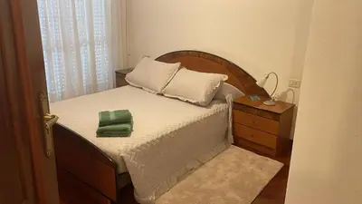 a bed with a wooden headboard and a nightstand with a green towel at Monte Faro El corazón de Galicia in Lalín