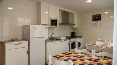 a kitchen with a refrigerator and a table with chairs at Albergue Castro Domum in Castrillo de Cabrera