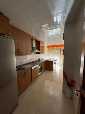 a large kitchen with wooden cabinets and a refrigerator at Piso de tres habitaciones frente al Puerto Deportivo in Viveiro