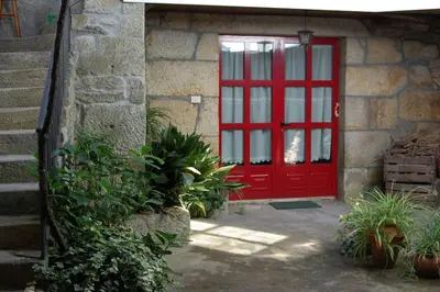 a red door on a stone building with plants at A Casa do Buxo in Casardeita