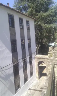 a white building with a fence next to a tree at Apartamento Tránsito de Entrerruas in Santiago de Compostela