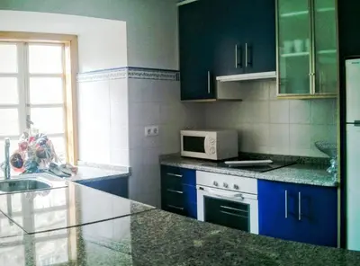 a kitchen with blue cabinets and a white refrigerator at Apartamento Tránsito de Entrerruas in Santiago de Compostela