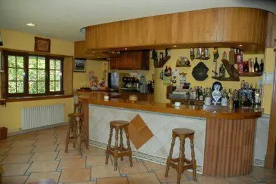 a kitchen with a bar with two stools at El Urogallo in Noceda