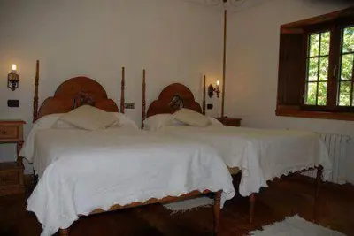 a bedroom with two beds with white sheets and a window at El Urogallo in Noceda