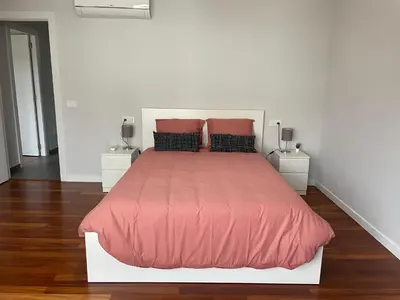 a white bedroom with a large bed with red comforter at Casa Pilar Primero in Sigüeiro