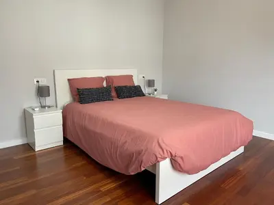a bedroom with a large bed with pink sheets and pillows at Casa Pilar Primero in Sigüeiro