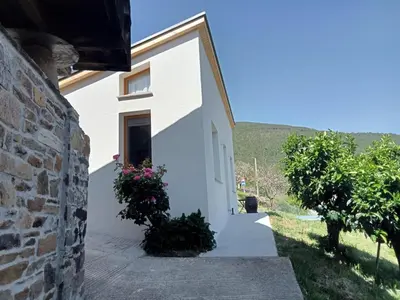 a white house with a stone wall at Mini Room Ron in Merou