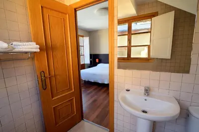 a bathroom with a sink and a toilet and a bed at Hostal El Palacio in Molinaseca