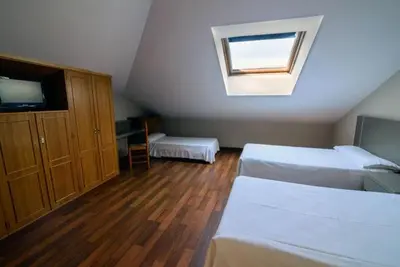 a attic bedroom with two beds and a window at Hostal El Palacio in Molinaseca