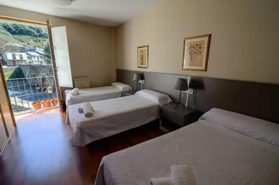 a hotel room with three beds and a window at Hostal El Palacio in Molinaseca