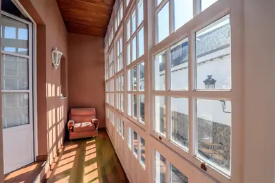a hallway with windows and a chair in a building at Hostal El Palacio in Molinaseca