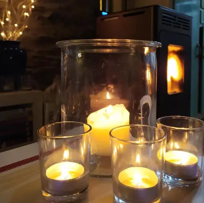 three candles in a glass jar on a table at Refugio Alto Sil in Páramo del Sil
