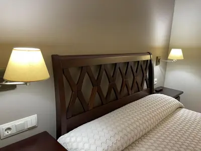 a bedroom with a bed with a wooden headboard and lamps at Apartamentos Río Sil in Sober