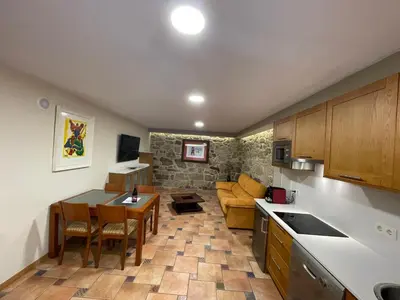 a kitchen and living room with a table and a couch at Apartamentos Río Sil in Sober