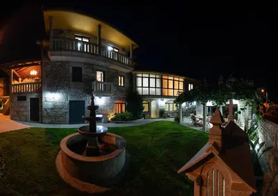 a large house with a fountain in front of it at night at Apartamentos Río Sil in Sober
