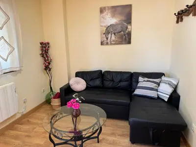 a living room with a black couch and a glass table at Apartamentos Sanabria in Galende