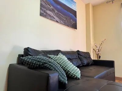 a black leather couch with pillows on it at Apartamentos Sanabria in Galende