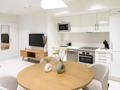 a white kitchen with a wooden table and chairs at Loft América 32-0 in Melide