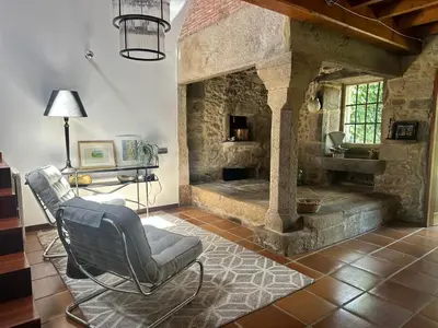 a living room with a chair and a stone fireplace at Casa do Bidueiro in Luou