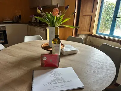 a table with a bottle of wine and a vase with flowers at Casa do Bidueiro in Luou