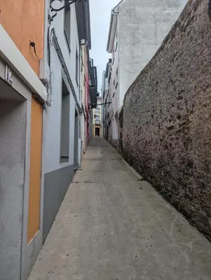 an alley between two buildings and a wall at Casa Muralla in Ribadeo
