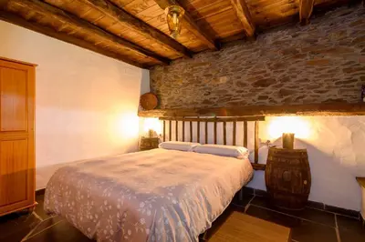 a bedroom with a bed and a stone wall at As Casias d'Oscos in Villanueva de Oscos
