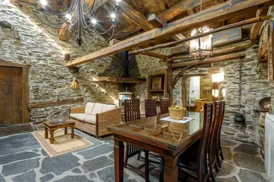 a dining room with a wooden table and a couch at As Casias d'Oscos in Villanueva de Oscos