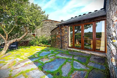 a stone house with a patio with a window at As Casias d'Oscos in Villanueva de Oscos
