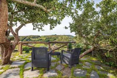 two chairs sitting next to a table under a tree at As Casias d'Oscos in Villanueva de Oscos