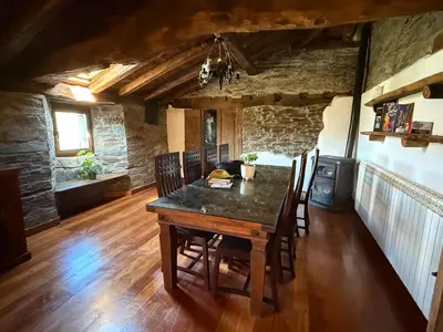 a dining room with a wooden table and chairs at As Casias d'Oscos in Villanueva de Oscos
