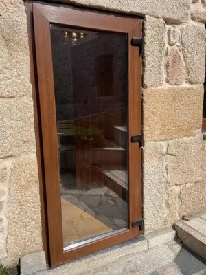 a glass door in a stone building with a brick wall at O Lar Do Bispo in Arbo