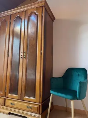a green chair sitting next to a wooden cabinet at O Lar Do Bispo in Arbo