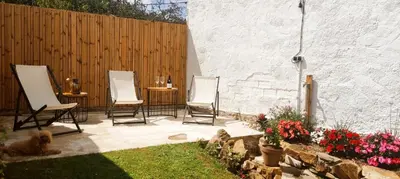 a patio with three chairs and a wooden fence at Casita con jardin en Sada in San Andrés de Carnoedo